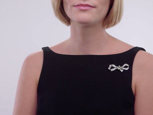 Diamond and pearl bow brooch pinned to a black dress
