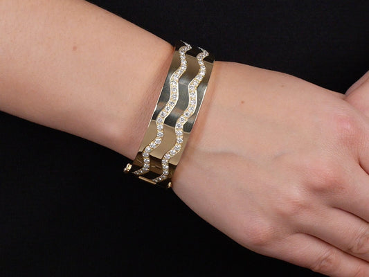 Wrist wearing an 18K yellow gold diamond bangle