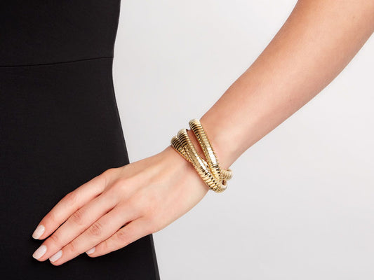 Three interlocking yellow gold tubogas bracelets on wrist