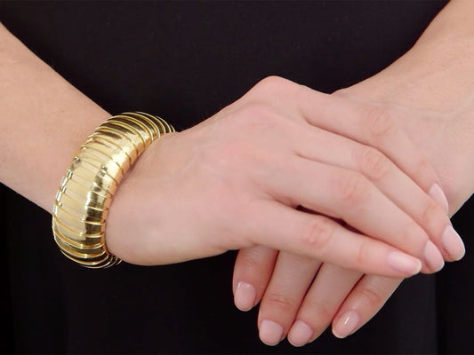 Wide polished gold domed cuff bracelet on wrist