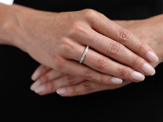 Platinum diamond band ring worn on folded hands