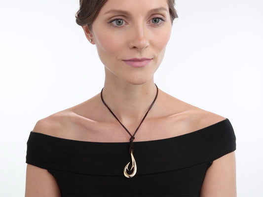 Woman wearing a gold fish hook pendant on leather cord