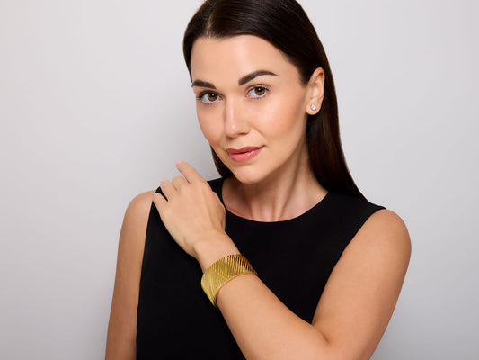 Woman wearing a wide fluted 18K gold bangle bracelet