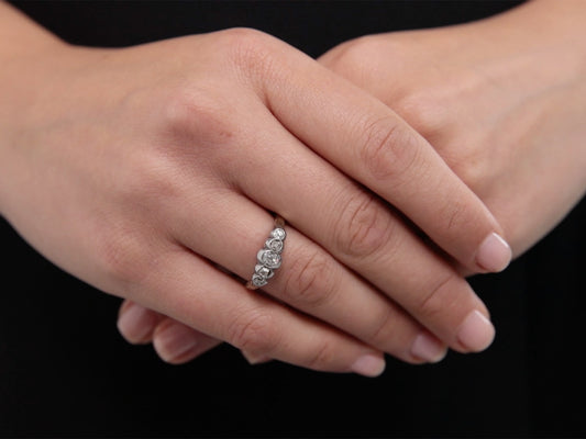 Five stone diamond ring in gold and silver on folded hands