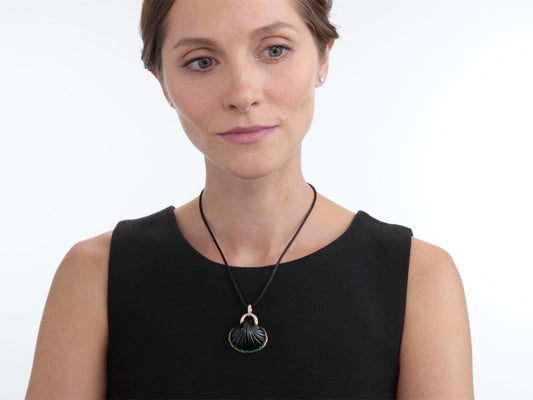 Model wearing a carved onyx shell pendant with green enamel frame