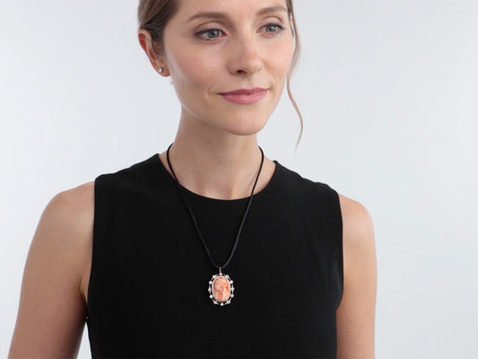 Woman wearing a coral cameo pendant with diamond border