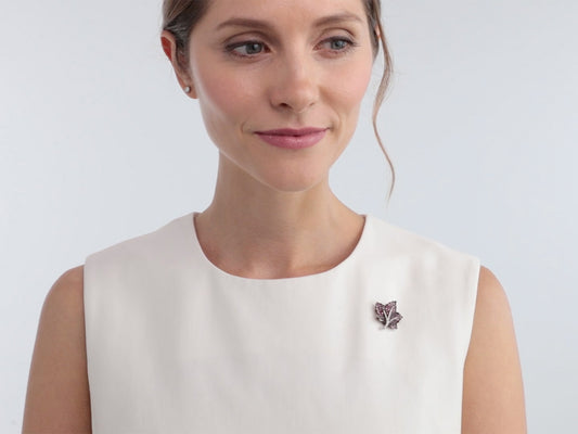 Woman wearing a small pink sapphire and diamond leaf brooch