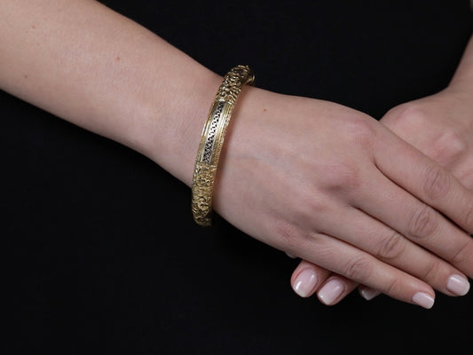 18K yellow gold hinged bangle with foliate carving on wrist
