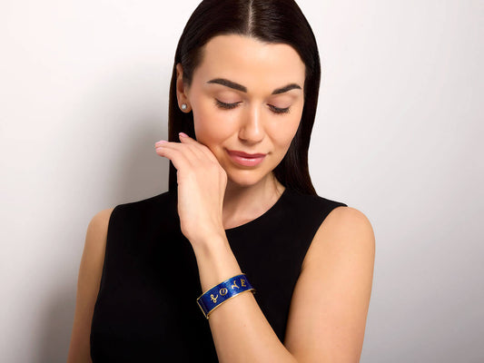 Woman wearing a blue enamel Love bangle with gold trim