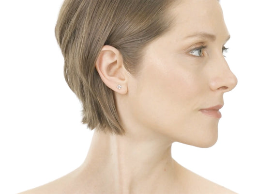 Woman wearing a diamond cross stud earring in profile