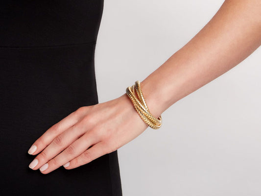 Three interlocking 18K yellow gold tubogas bracelets on wrist