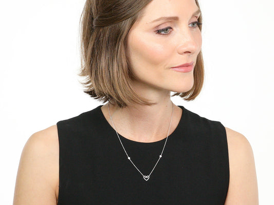 Woman wearing a delicate white gold heart pendant necklace