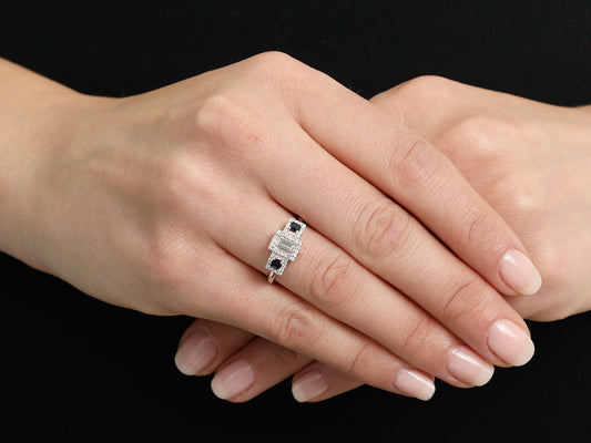 Hands displaying a step cut diamond and sapphire ring