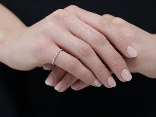 Hands wearing a thin micro pavé diamond band