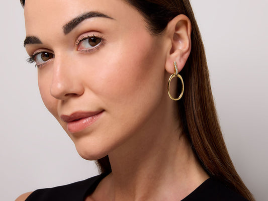 Model wearing an oval gold hoop earring with diamond top