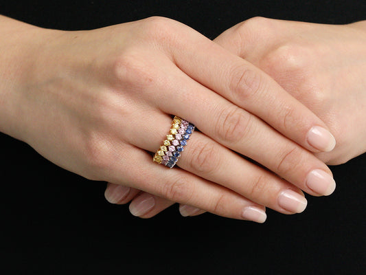 Hands wearing three stacked sapphire bands in gold
