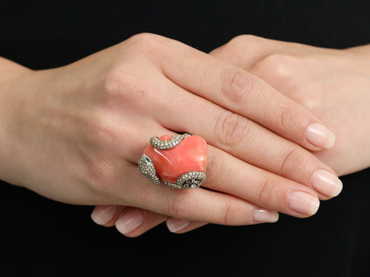 Coral and diamond snake ring worn on clasped hands