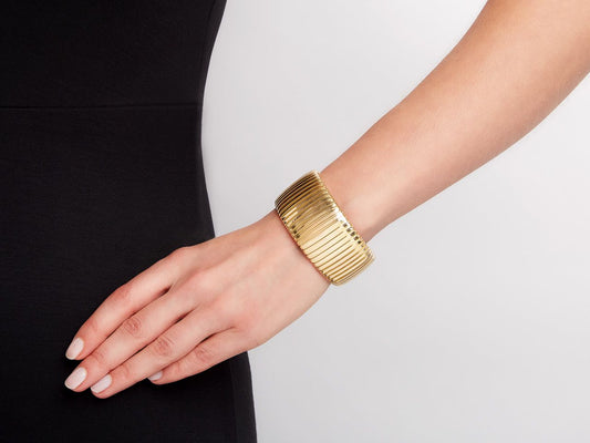 Wide 18K gold tubogas cuff bracelet worn on wrist