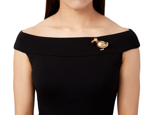 Gold duck pin with ruby accents on a black dress