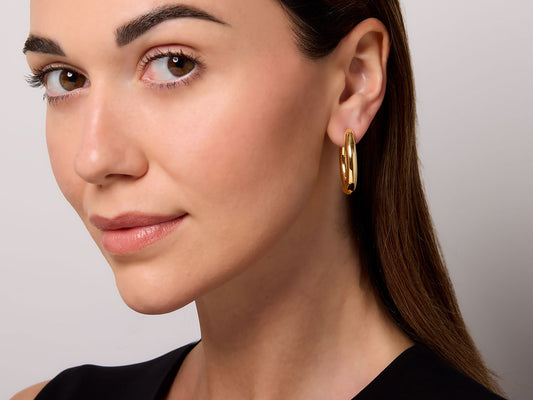 Woman wearing a polished elongated gold hoop earring