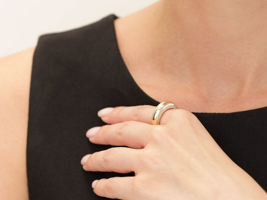 Hand wearing a polished gold ring with diamond set edges