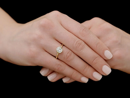 Hand wearing a gold bezel set diamond ring