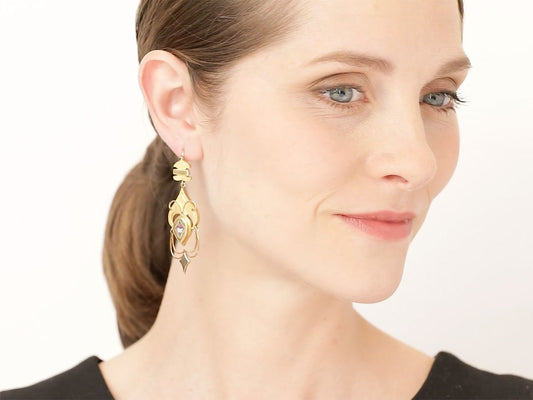 Woman wearing ornate gold enamel pansy earrings