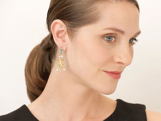 Woman wearing an ornate gold and enamel drop earring