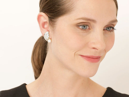 Woman wearing a diamond and pearl leaf earring in gold