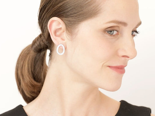 Woman wearing oval diamond hoop earrings in white gold