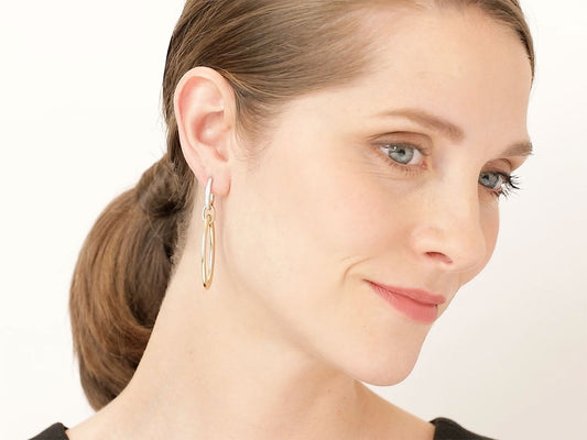 Model wearing an elongated gold hoop earring with diamond top