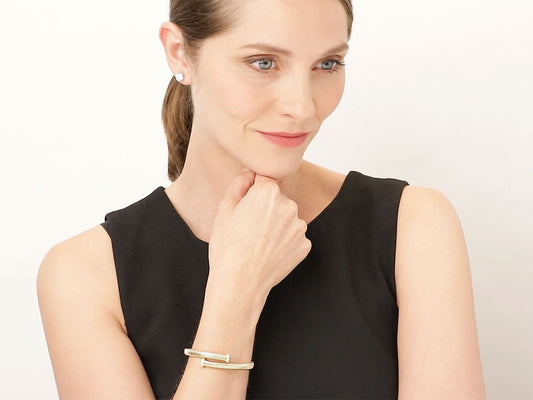 Woman wearing an 18K yellow gold bypass bracelet with nail head terminals