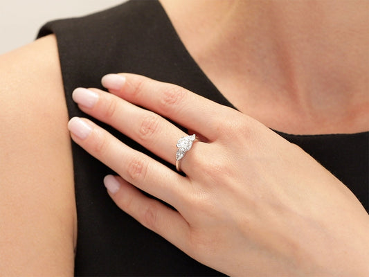 Hand wearing a diamond solitaire ring with pear shoulders