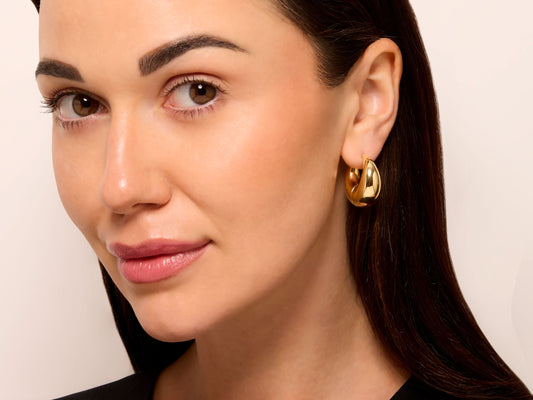 Model wearing a polished 18K gold crescent hoop earring