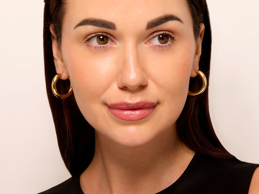 Woman wearing narrow 18K gold hoop earrings