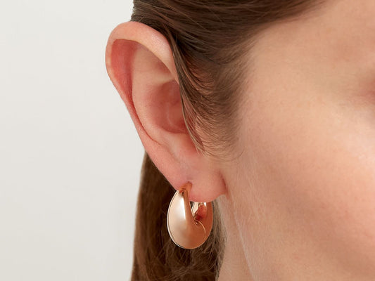 Close up of ear wearing a small polished rose gold hoop earring