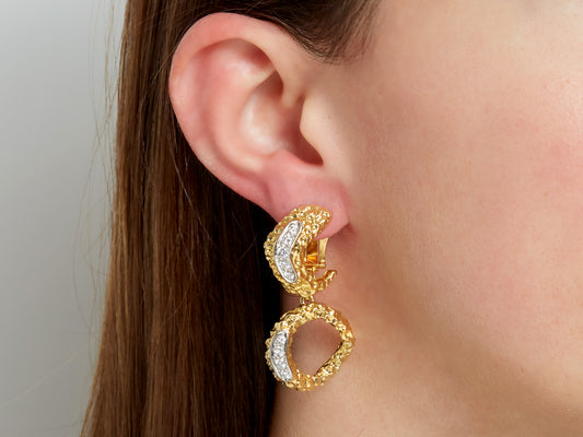 Close up of a textured 18K gold diamond drop earring