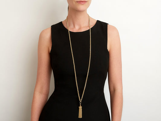 Long 14K gold tassel necklace on woman in black dress