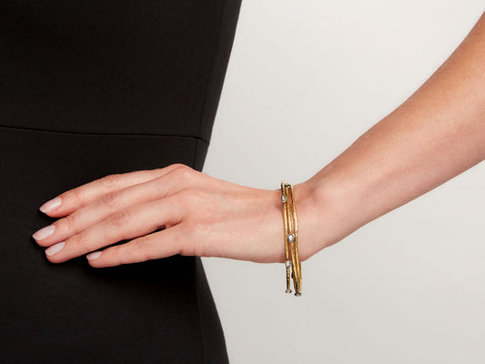 Three gold and silver bangles worn on a wrist