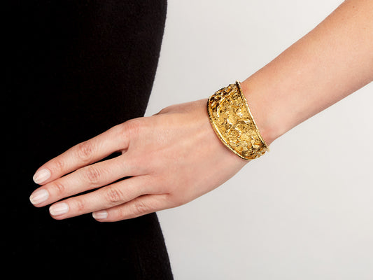 Hand wearing a wide hammered 22K gold cuff bracelet