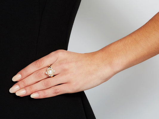 Hand wearing an 18K gold pearl and diamond ring