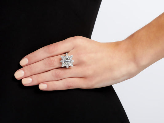 Hand wearing a platinum emerald cut diamond ring with halo