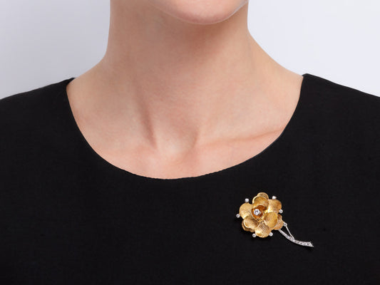Gold flower brooch with diamonds worn on black top