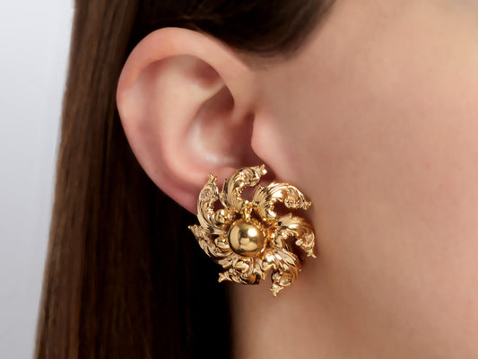 Gold floral swirl earring worn on ear