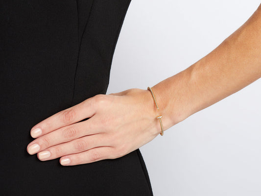 Thin 18K yellow gold nail bracelet on a wrist