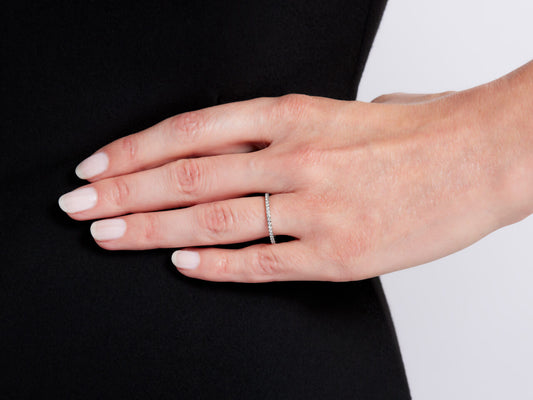 Hand wearing a thin white gold diamond eternity band