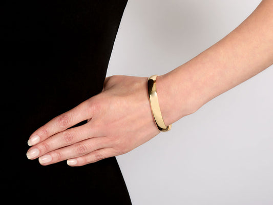 Polished 18K yellow gold flexible cuff bracelet on wrist