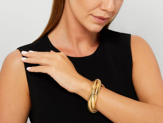 Three interlocking 18K yellow gold tubogas bracelets on wrist