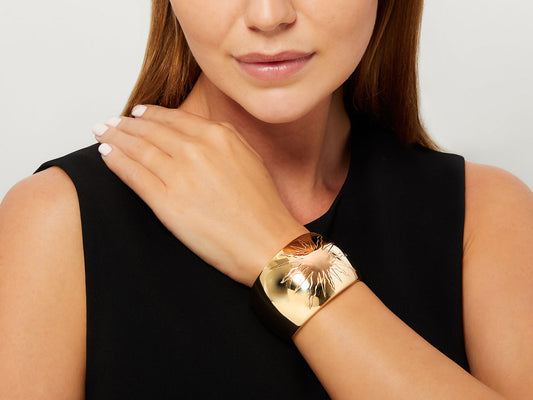 Woman wearing a polished gold sun motif cuff bracelet