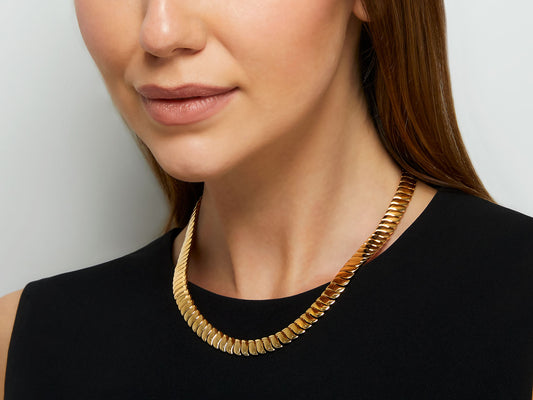 Woman wearing a polished 18K gold flexible link necklace